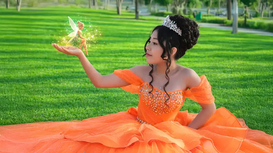 Quinceanera portrait in a green park with an orange gown.