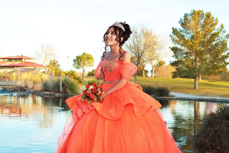 Quinceanera portrait beside the water in warm evening light.